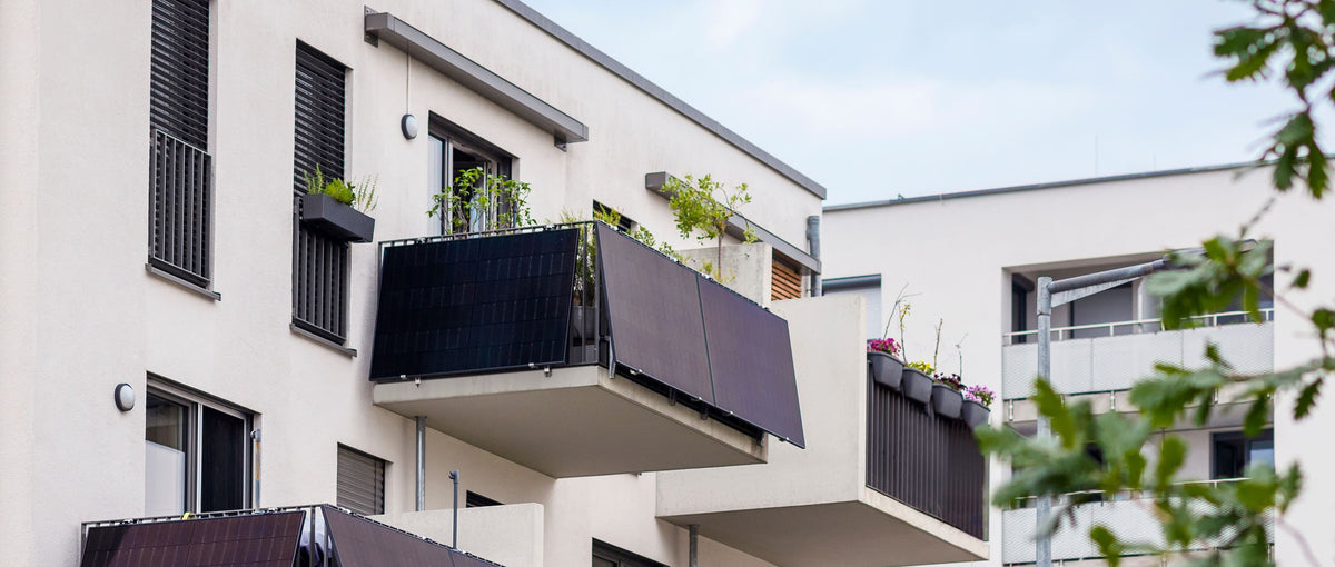Mehrfamilienhaus mit Balkonkraftwerken: schräg an den Balkongeländern montierte Solarmodule